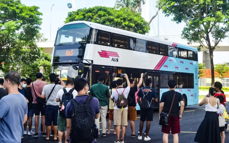 Crowd gathered around double‑decker bus.