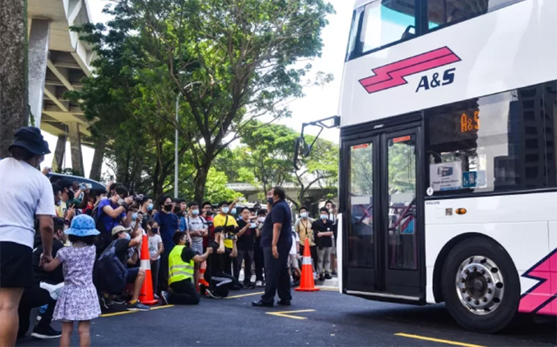as-doubledecker-bus-arriving-at-a-pickup-point-with-a-crowd-gathering-outside